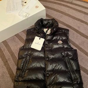 Moncler väst tibb gilet  - Moncler väst svart av modellen ”tibb gilet” i storlek 0 (motsvarar ungefär XS). Använd men i gott skick. Säljs med original förpackning samt tillbehör. 