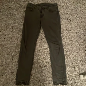 Grå jeans från Levi's - Snygga grå Levi's jeans i modell 512 med en slim passform. De har en klassisk femficksdesign och är tillverkade i ett bekvämt denimtyg. Perfekta för en stilren look.