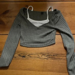 Grön ribbad topp från Shein - Säljer en grön ribbad topp från Shein i storlek XS. Toppen har en v-ringad design och långa ärmar, perfekt för en stilren look. Den är croppad och passar bra till både jeans och kjol. Den är oanvänd. Priset kan diskuteras 