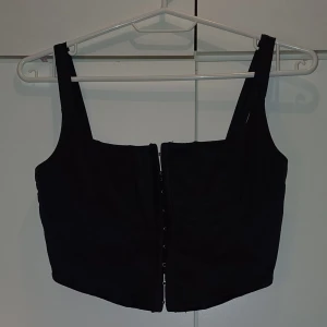 Svart korsett topp - En svart korsett liknande topp. Den är lite kortare men är extremt snygg med ett par jeans. Gör ont att sälja då jag älskar den men den passar inte längre.