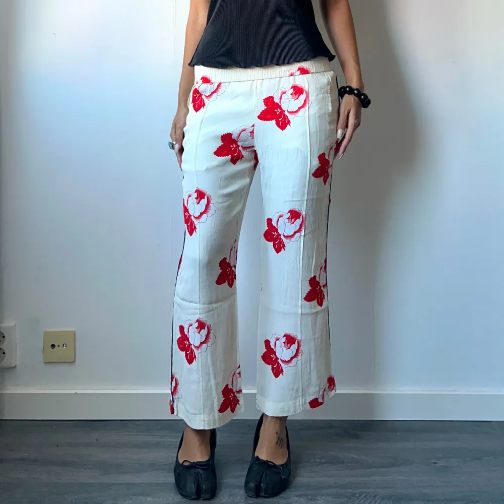 •Cream white straight leg crepe trousers with red flower print, from scandi brand Ganni. Small hole on front  • SIZE - S / EU 36 • BRAND -  Ganni • MATERIAL - 100% viscose. Jeans & Byxor.