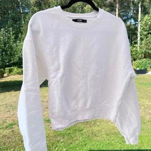 Vit sweatshirt - Vit sweatshirt från Bikbok i storlek XS. Den är lite snyggt oversized på mig som normalt bär storlek S 🤍 Säljer pga att den inte används längre! 🌸  Längd: 51 cm Axel: 56 cm Byst: 106 cm