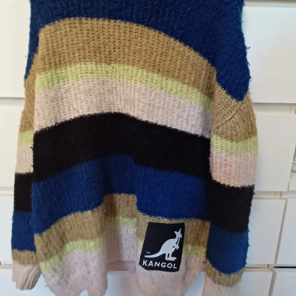 Denna stickade tröja är i storlek XS fast är jätte stor i storleken. Tröjan känns som en XL och kan tämjas ut väldigt enkelt den är 5-färgig som man kan se på bilden. Tröjan har ett stort kangol märke nere på tröjan .färgerna finns vid taggarna.. Neuleet.