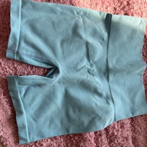 Ljusblå kortärmad topp - Säljer ett ljusblåt träningsett som är mjukt och stretchigt material. Perfekt för träning eller en avslappnad dag. Toppen har en ribbad kant vid ärmslut och nederkant för en bekväm passform.