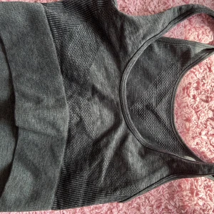 Grå ribbad linnetopp - Säljer en snygg grå ribbad linnetopp. Perfekt för träning eller en avslappnad dag. Toppen är ärmlös och har en tight passform som framhäver figuren. Materialet är mjukt och stretchigt för extra komfort.