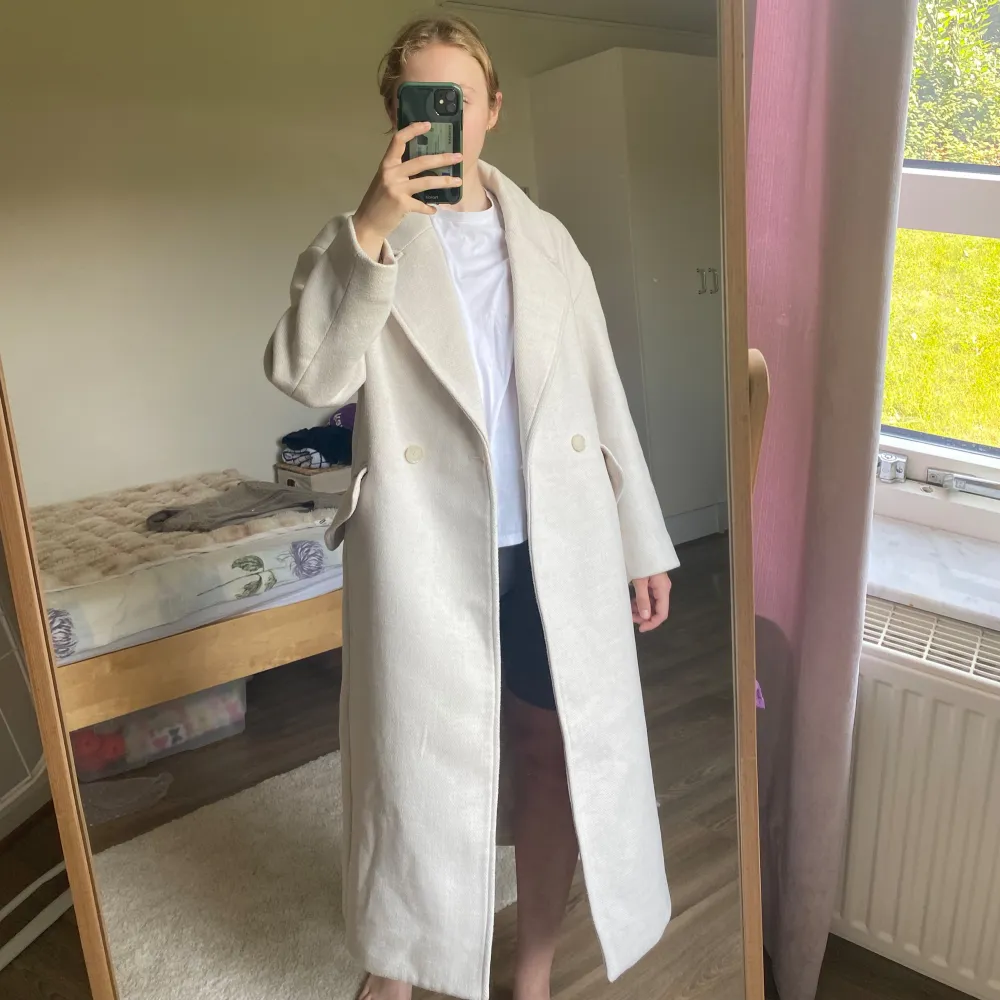Beige kappa från H&M. De två sista bilderna visar färgen bäst. Fint skick. Lite nopprig på vissa ställen, men jag har använt noppborttagare så det är knappt märkbart. Den har ett märke (bild 4), men det döljs om man stänger kappan & är ganska diskret. Takit.