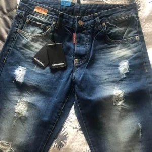 Blå jeans från Dsquared2 - Snygga blå jeans från Dsquared2 med slitna detaljer och en cool tvätt. De har en klassisk femficksdesign och knappar i gylfen. Perfekta för en trendig look.