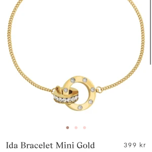 Ida Bracelet Mini Gold - Elegant armband i guld med en cirkulär detalj prydd med gnistrande stenar. Perfekt för att ge en touch av lyx till din stil.