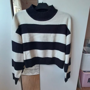 Stickad halvpolo tröja - Säljer en snygg svart-vit randig tröja från H&M . Tröjan har en kort passform med långa armar med halvpolo💕 Den är tillverkad i ett mjukt material som känns skönt mot huden. Sällan använd! 
