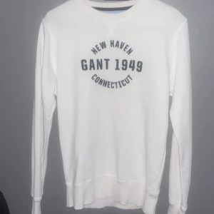 Vit långärmad tröja från Gant - Säljer en stilren vit långärmad tröja från Gant med tryck 'New Haven Gant 1949 Connecticut' på framsidan. Perfekt för en avslappnad look.