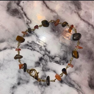 Armband med karneol och tigeröga - Unikt armband med karneol och tigeröga stenar , fästade på en guldkedja. Armbandet har ett dekorativt lås som ger en elegant touch. Handgjord av oss på Dahlia UF🤎🧡