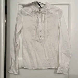 Vit blus från Custommade - Helt oanvänd med kvitto kvar. Stilren, långärmad blus med knäppning och knytband fram. 