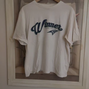 Vit t-shirt med tryck från lager 157 - Säljer en vit t-shirt från lager 157 med ett coolt tryck i blått och grönt där det står 'Winner College Streets NYC'. 