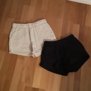 Beige och svarta shorts - Två par shorts i beige och svart. Mjuka och sköna. Ett par- 50kr, båda- 80kr. De har elastisk midja med dragsko och sidofickor. 