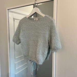Ljusblå fluffig tröja  - Ljusblå tröja med öppen rygg från NA-KD x Hanna Schönberg, mjuk Inge stickig! I storlek M