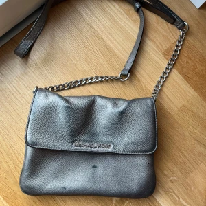 Vintage silvrig väska från Michael Kors - Fantastiskt skick, typ aldrig använd. Köpt vid tidigt 2000-tal för över 2000 kr. Inga defekter, märken, hål. Den ska se ut som den gör. Stockholmsstil -aktig. Diskuterar gärna pris!!!!