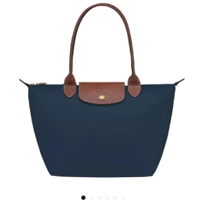 Blå axelväska från Longchamp - Den jättesnygga populära longchamp väskan, har en liten defekt på baksidan men kan nog gå bort med vatten eller våtservett. Nypris 1600kr. Skriv om ni vill ha fler bilder 💝💝 priset går att diskutera 28x26,5x15,5 är måtten. 