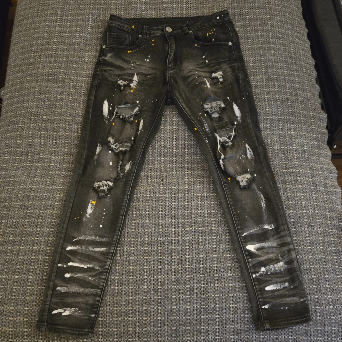 Svarta jeans med slitningar och färgstänk