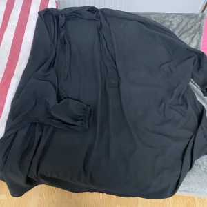 Svart jilbab  - Elegant svart jilbab med långa ärmar och knytband i midjan. Perfekt för en stilren look.