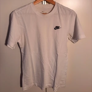 Vit t-shirt från Nike - Säljer en klassisk vit t-shirt från Nike med korta ärmar och en broderad logga på bröstet. Perfekt för en enkel och stilren look. Storlek XS. Knappt använd!
