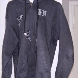 Rhinestone hoodie  - Säljer en svart rhinestone hoodie med coola broderade detaljer av änglar och texten 'GUARDIANS' på ryggen. Tröjan har en klassisk passform med dragkedja och fickor framtill. Perfekt för en avslappnad stil.