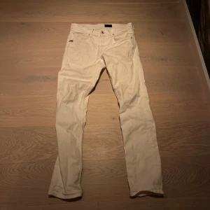 Beige byxor från Tiger of Sweden - Snygga beige byxor från Tiger of Sweden med en stilren design. Byxorna har en klassisk passform med knappar och dragkedja framtill. Perfekta för en stilren look.