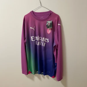 Ac Milan fotbollströja (tredje ställ 23/24) - Snygg långärmad fotbollströja från Puma med AC Milan-logga. Tröjan har en cool färgövergång från lila till blå och grön, med sponsorloggor från Emirates och wefox. Perfekt för fotbollsfans som vill sticka ut på planen! HELT NY & KVITTO FINNS‼️