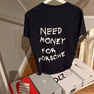Svart t-shirt med text - Snygg svart t-shirt med texten 'Need Money for Porsche' i vit på baksidan. Perfekt för en avslappnad stil med en humoristisk touch. 