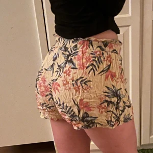 Blommiga shorts, H&M  - Luftiga och blommiga shorts från H&M i en härlig gul färg med blommor och andra växter på. De har en bekväm passform med knytband i midjan, ej justerbar. Dock är dem väldigt stretchiga i midjan! Skulle uppskatta storleken som XS men passar även S. Perfekta för varma sommardagar☀️😎