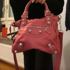 Rosa citybag från Balenciaga - Intressekoll på min älskade rosa skinnväska från Balenciaga med silverfärgade detaljer och dragkedja. Väskan har både handtag och en justerbar axelrem för flexibel användning. Såå sjukt snygg och touchar upp en outfit såå mycket🤩lägg prisförslag. Har äktahetsbevis!