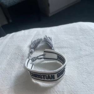 Vitt armband från Christian Dior - Justerbart Christian dior armbandsom inte kommer till andvända. Är i nytt skick och priset sitter inte inristat i sten.