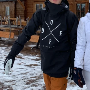 Svart jacka från Dope - Snygg svart jacka från Dope med stor logga på framsidan. Jackan har en hög krage med snörning och en praktisk magficka. Perfekt för kyliga dagar. Inga skador eller tecken på användning. 