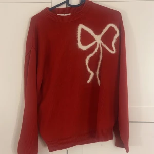 Röd tröja med rosett från H&M - Säljer en röd tröja från H&M med en stor vit rosett på framsidan. Har bara använt 1 gång så den är i väldigt bra skick! Strl 158/164