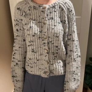 Grå stickad kofta med knappar - Mysig grå stickad kofta med knappar framtill. Koftan har ett melerat mönster i mörkare grå toner och långa armar🩷vet ej vilken butik den är köpt i då den är från USA