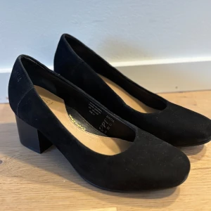 Svarta mockapumps från Dasa - Eleganta svarta pumps i mocka från Dasa med en bekväm blockklack. Perfekta för en stilren look. Klacken är 5.5cm hög.