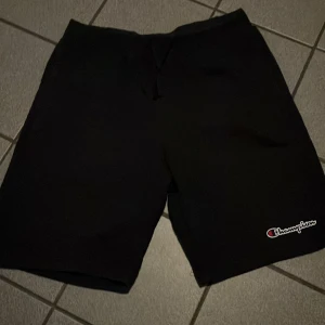 Svarta shorts från Champion - Snygga svarta shorts från Champion med logga på benet. Perfekta för en avslappnad stil. Tillverkade i ett bekvämt material som passar bra för olika aktiviteter.