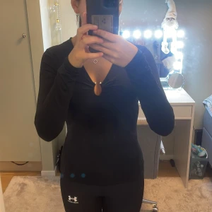 Svart långärmad topp från H&M - Säljer en stilren svart långärmad topp från H&M med en v-ringad design och dekorativ knutdetalj framtill. Perfekt för en chic och enkel look. Passar bra till både jeans och kjol. Använd få gånger. 