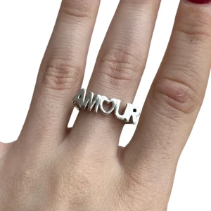 Silverring med text 'Amour' - Stilren silverring från L8 Hasselblad med texten 'Amour' där bokstaven 'O' är formad som ett hjärta. Låda tillkommer, säljer då jag blivit en guld person. Köpt för 1100 kr säljer nu för 750 kr