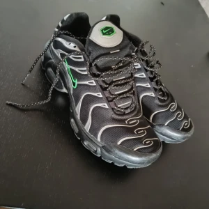 Svarta Nike sneakers med gröna detaljer - Snygga svarta Nike sneakers med unikt mönster och gröna detaljer. Skorna har en robust sula med bra grepp och snörning för optimal passform. Perfekta för en sportig look.