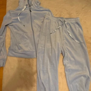 Ljusblå velour hoodie och byxor från Gina Tricot - Mysig ljusblå velour hoodie med dragkedja och matchande byxor från Gina Tricot. Hoodien har snören i huvan och byxorna har en bekväm resårmidja med knytband. Byxorna är i storlek S och tröjan i Xs