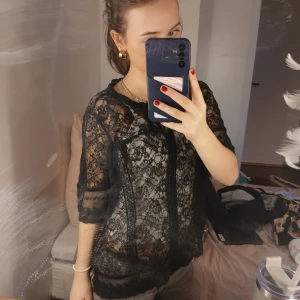 Svart spetsblus - Säljer en elegant svart spetsblus med trekvartsärm. Blusen har ett vackert spetsmönster och en rund halsringning. Osäker på märke, men passar mig som bär xs/s jättebra💕