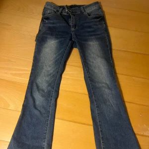 Blå bootcut jeans - Snygga blå bootcut jeans med klassisk femficksdesign och knappgylf. Perfekta för en avslappnad stil.