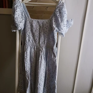 Ljusblå klänning från NA-KD - Charmig ljusblå klänning från NA-KD med broderade blommor och korta puffärmar. Perfekt för sommarens varma dagar. Klänningen har en elastisk midja för en bekväm passform, den är i mycket fint skick. Priset kan diskuteras💖
