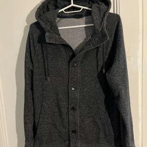 Cardigan med luva  - Mörkgrå cardigan med luva i toppenskick.Modellen på bilden är 174 o väger 56 ish,  Passar S eller stor Xs. Jag fraktar inom 24h via PostNord och tryck gärna på ”köp nu”. Snabba affärer underlättar, hör av er vid funderingar! Mvh 