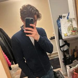 Mörkblå full zip - Säljer en stilren mörkblå full zip från Pier One med dragkedja och ribbad krage. Den är i storlek S och är perfekt för en stilren look