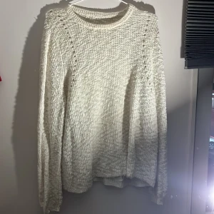 Beige stickad tröja - Mysig beige stickad tröja med långärmad design. Perfekt för kyligare dagar med sin klassiska stil och bekväma passform.