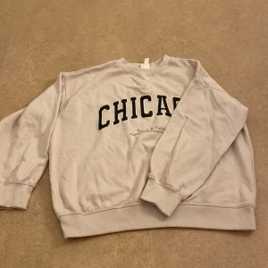Grå sweatshirt med texten 'CHICAGO' - Säljer en sweatshirt, i storlek M och det passar för xs och s, den är oversized tröja. Har knappast använt den.