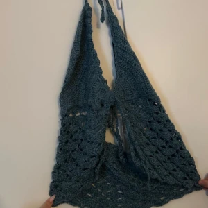 Blå virkad topp - Snygg grå egenvirkad topp med halterneck-design. Perfekt för sommardagar eller festivaler. Den har ett vackert mönster och knytband i nacken.