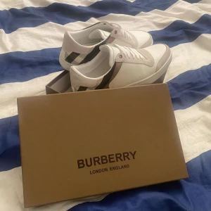 Burrberry skor - Säljer ett par stilrena vita sneakers från Burberry  storlek i mycket bra skick. Skorna har knappt tecken på användning. Är använda ett få tal gånger. Hör av er vid fler frågor