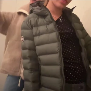Grön pufferjacka från Colmar - Säljer en snygg grön pufferjacka från Colmar. Jackan har en liten defekt se på sista bilden💕 bilderna är från förra ägaren!